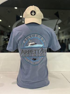 Blue t-shirt with Jarrett Bay Boatworks logo and beige cap on a white surface.